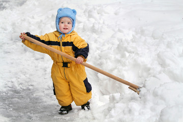 Little boy with big wooden shovel to clear snow. A very snowy wi