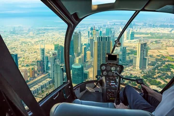 Selbstklebende Fototapeten Hubschrauber-Cockpit fliegt in Wolkenkratzern der Skyline der Innenstadt von Dubai an der Sheikh Zayed Road, Vereinigte Arabische Emirate, mit Pilotarm und Steuerplatine in der Kabine. © bennymarty