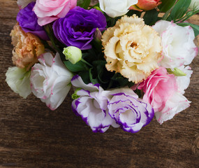 Pink, white, orange and violet eustoma flowers on aged wooden background