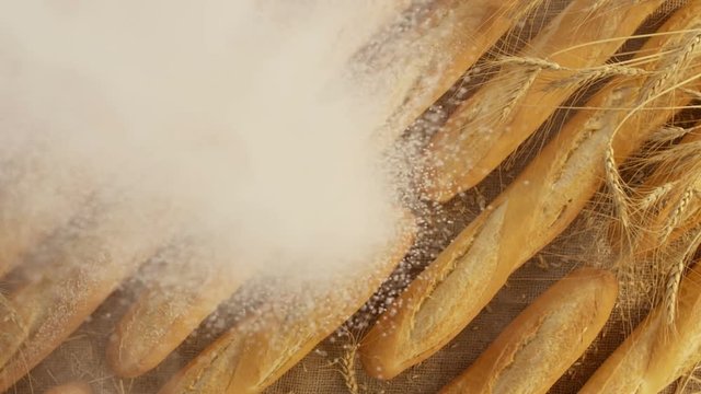 Beautiful composition of bread, flour and wheat. Flour falling on bread in slow motion. Shot on RED EPIC DRAGON Cinema Camera.