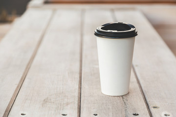 White plastic cup on a wooden table. To put your text.