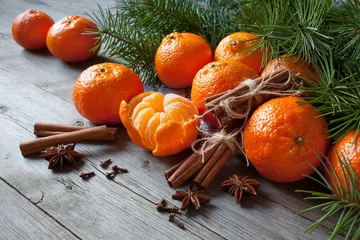 Poster  Tangerines with cinnamon, anise and fir branches on a wooden table. Christmas background card with fruits. © tachinskamarina