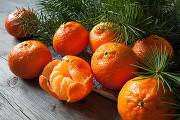 Fototapeta na wymiar Tangerines on a wooden table with branches of fir