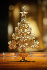 Ornament - Christmas Tree / Sparkling christmas tree ornament stands on polished wood table top. Background booked.