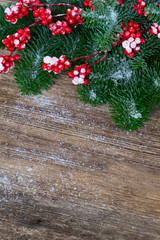 red and white christmas - twig with red berries and green evergreen tree on wooden background with copy space