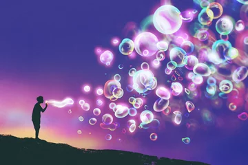 Tuinposter young man blowing glowing soap bubbles against evening sky,illustration painting © grandfailure