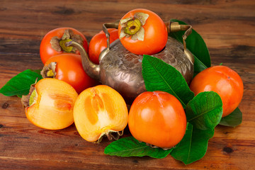Persimmon kaki fruit with vintage tea pot. Oriental East Persian still life.