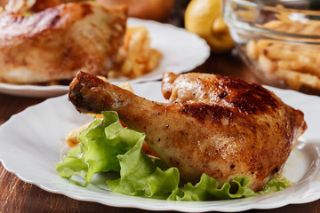 Roasted chicken legs with french fries and lettuce