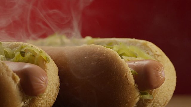 Appetizing steaming hot dog on red background. Shot on RED EPIC DRAGON Cinema Camera.