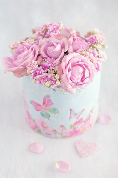 Lovely bunch of flowers .Beautiful fresh roses flowers in a box decorated with a heart on a pink background with texture .