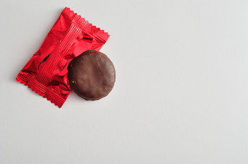 A round biscuits covered in chocolate with a red wrapper