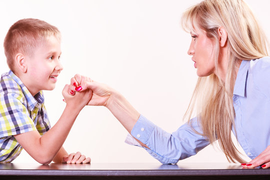 Mother And Son Arm Wrestle Sit At Table.