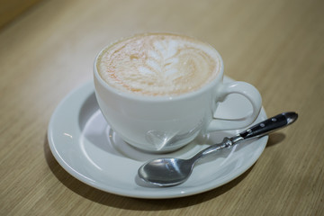 Coffee cappuccino in white cup and white mobile phone on the table in a cafe
