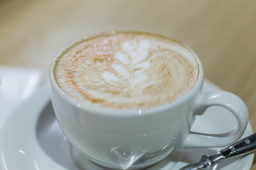 Coffee cappuccino in white cup and white mobile phone on the table in a cafe
