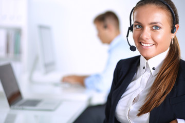 Happy female wearing headset and sitting on the desk