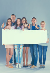 Happy young group of people standing together and holding a blank
