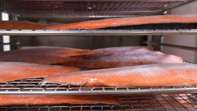 Many pieces of salmon fillet on the shelves ready for smoking.