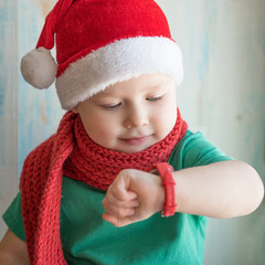 Adorable boy in Santa hat looking time