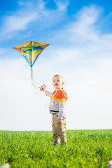 Young boy flies his kite in an open field. Little kid playing with kite on green meadow. Childhood concept.