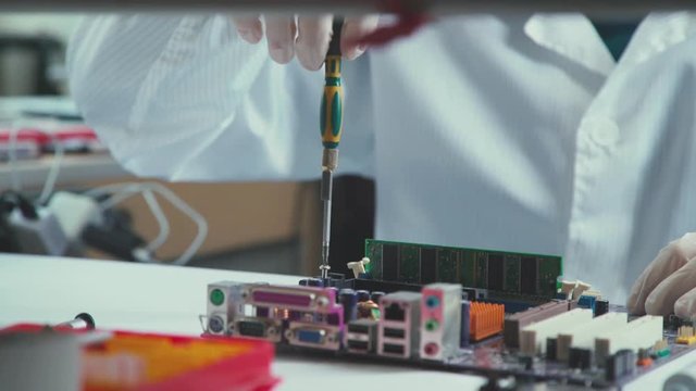 Repair of laptops and computer motherboards, using a screwdriver. Printed Circut Board. Stand for chips. Close-up: the motherboard. Hands of the master repair of computer technology and microchips.