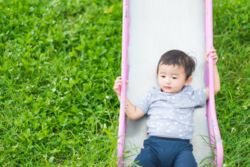 Little Asian kid playing slide at the playground