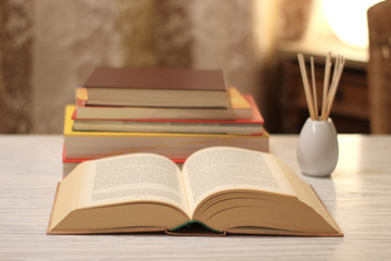 aufgeschlagenes Buch und Bücherstapel  auf einem Tisch
