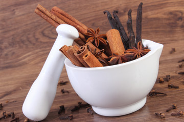 Fragrant anise, cinnamon and vanilla sticks in mortar on rustic board