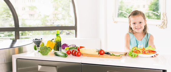 Cute little girl making salad. Child cooking. Healthy food