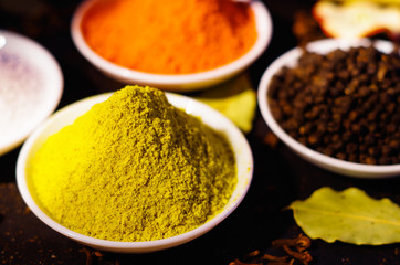 White bowls spread out with different colorful spices inside, beautiful rustic setting, spice and herbal concept