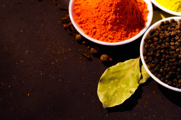 White bowls spread out with different colorful spices inside, beautiful rustic setting, spice and herbal concept