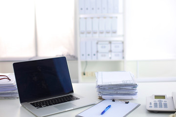 Laptop with stack of folders on table  white background