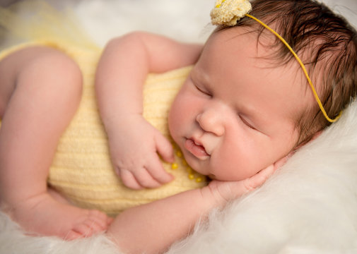 lovely baby in yellow romper sleeping with legs crossed