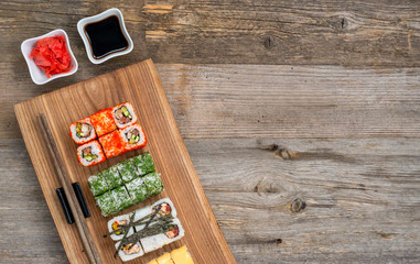 set of sushi and rolls with chopsticks on wooden table