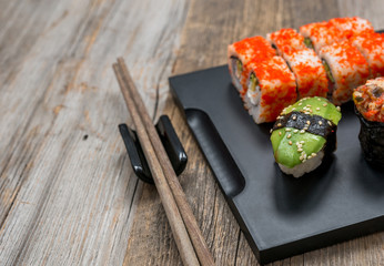 set of sushi and rolls with chopsticks on wooden table