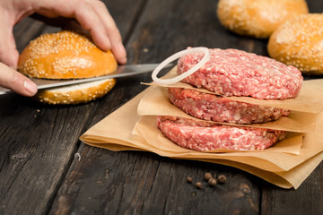 Raw ground beef meat cutlets with onion ring on table