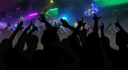 Fototapeta na wymiar Silhouettes of concert crowd with hands raised at a music disco