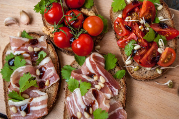 Fototapeta na wymiar Snack of bread (baguette), bacon (ham), tomatoes, balsamic and spices. Good beer and wine. Love for a European healthy raw food concept.