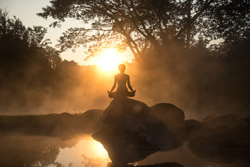Silhouette of a beautiful Yoga woman in the morning at the hot spring park, soft and select focus.