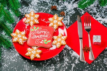 Beautifully laid Christmas table with gingerbread cookies on red plate with Cutlery knife and fork. Merry Christmas