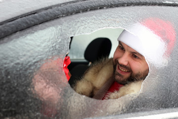 man in a red cap of Santa Claus in a car with broken glass