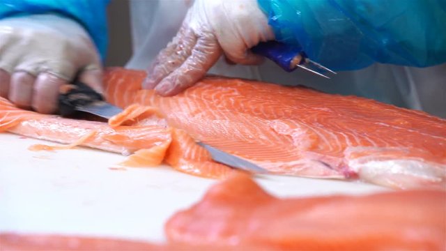 Man Slicing A Fillet Of Salmon At Table In A Fish Shop.