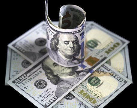 Hundred us dollar banknote standing on several hundred usa dollars bills shaped as octagon. Close up image. Isolated on black background.