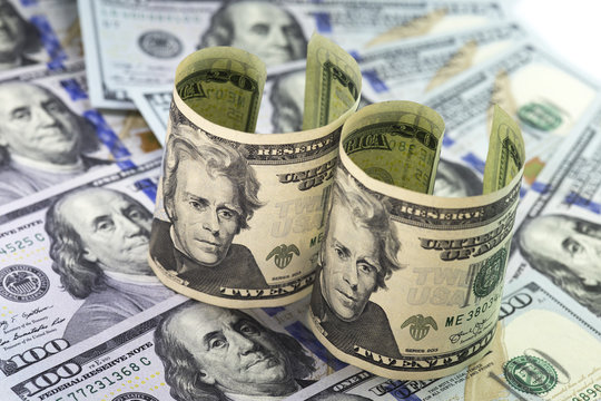 Two twenty dollars bills standing on hundred dollars bills backg