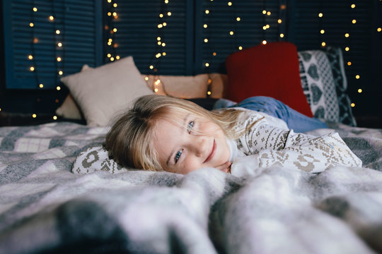 cute little girl in a sweater on the bed on a winter day
