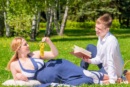Pregnant woman with grape and her husband with a book on the pic