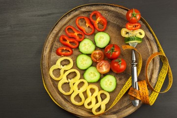 Mixed vegetables on a fork. Diet concept. The risk of obesity. Fresh food diet. Raw vegetables on a black table.
