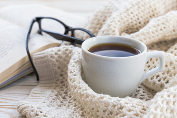 Warm knitted plaid, glasses, cup of hot coffee and book