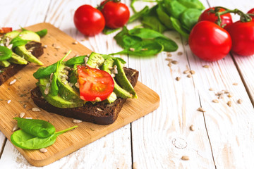 Toast with sliced avocado, tomatoes, spinach and spices