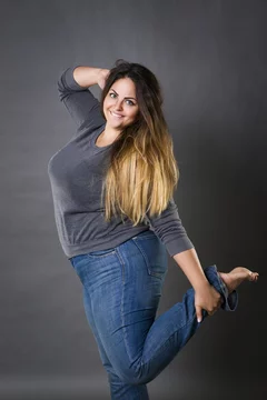 Young beautiful plus size model in blue jeans, xxl woman on gray background  Stock Photo | Adobe Stock