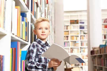 Dziecko czyta książkę w bibliotece szkolnej - obrazy, fototapety, plakaty
